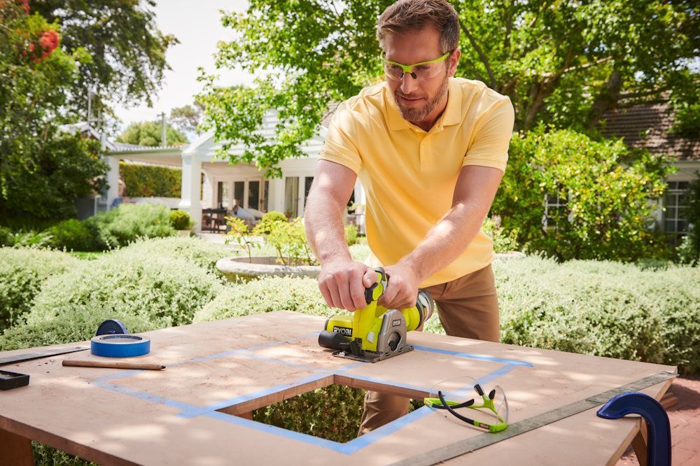 Person sägt Holzplatte mit Stichsäge